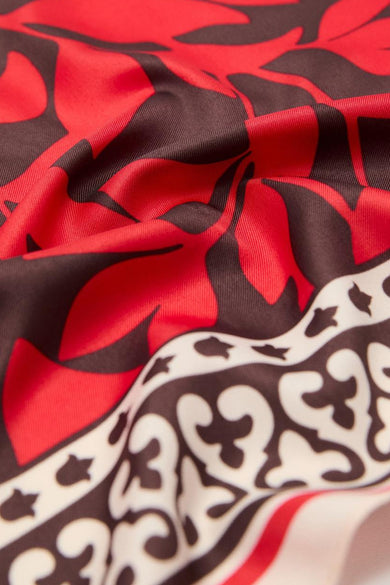 Foulard rouge en soie, de MANGO, à motifs floraux et bordure ornementale, avec un effet de tissu froissé.
