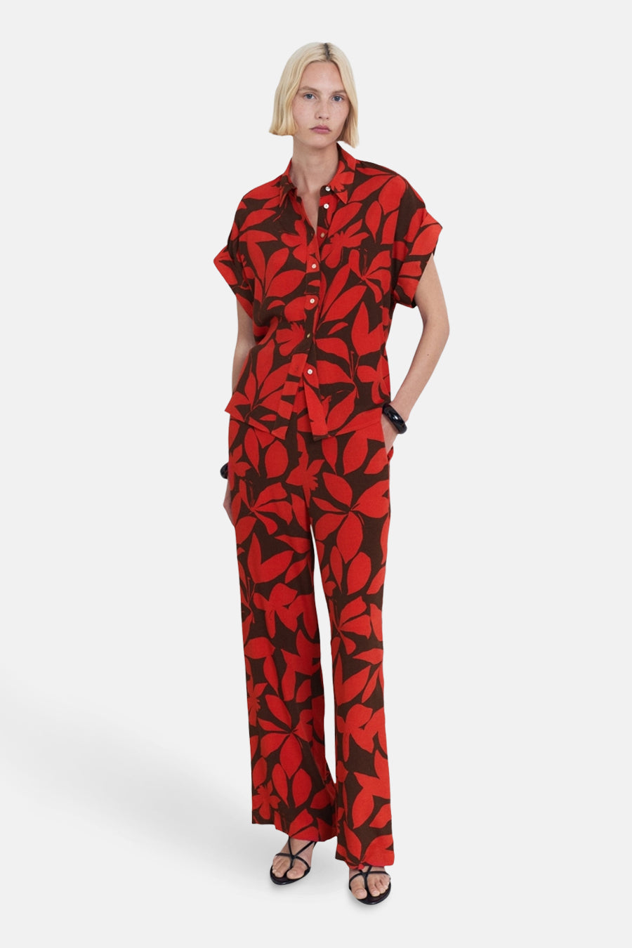 Chemise à manches courtes rouge par MANGO, à motif de feuilles marron portée avec un pantalon assorti.