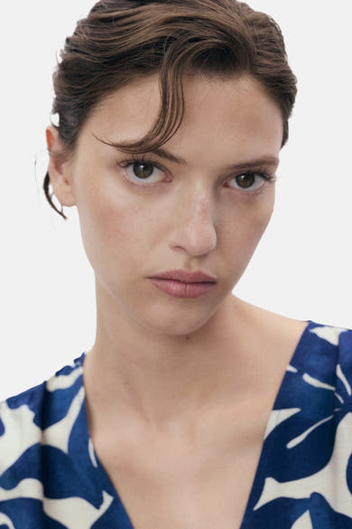 Blauwe jurk van MANGO met wit en blauw bloemenpatroon, gedragen door een vrouw met bruin haar.