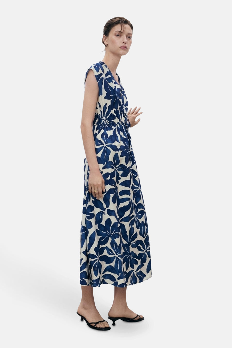Blauwe bloemenjurk van MANGO, met een elastische taille, gedragen met zwarte hakken.