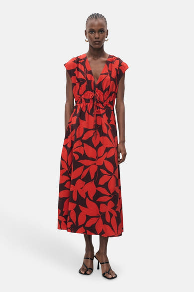 Rode jurk met bloemenprint van MANGO, met een aansluitende taille met trekkoord en zwarte hakken.