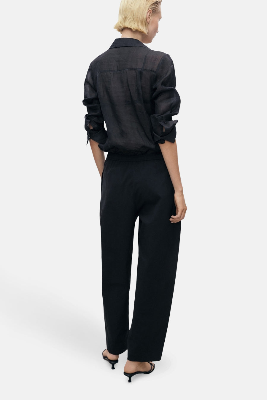 Zwarte broek van MANGO, rechte pasvorm, gedragen met een zwart linnen overhemd en muiltjes met hak.