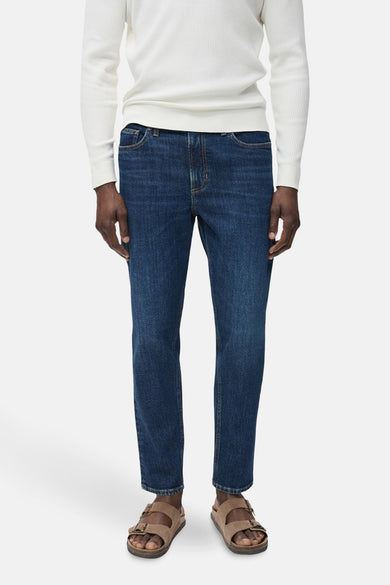 Donkerblauwe skinny jeans van MANGO, gedragen met een witte trui en lichtbruine sandalen.