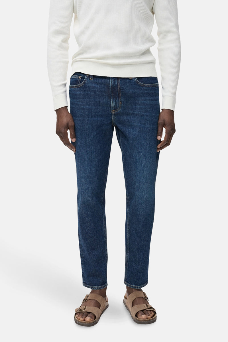 Donkerblauwe skinny jeans van MANGO, gedragen met een witte trui en lichtbruine sandalen.