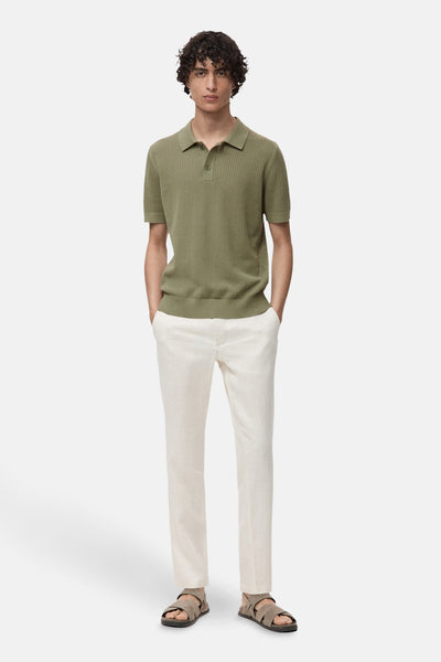 Kaki poloshirt met korte mouwen van MANGO, geribbelde textuur, gedragen met een lichte broek en sandalen.