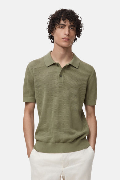 MANGO poloshirt met korte mouwen en een open structuur, gedragen met een witte broek.