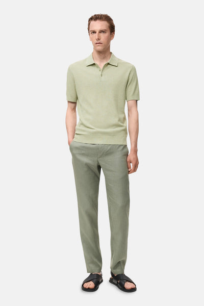 Groen poloshirt met korte mouwen van MANGO, in ribgebreid, gedragen met een linnen broek en zwarte sandalen.