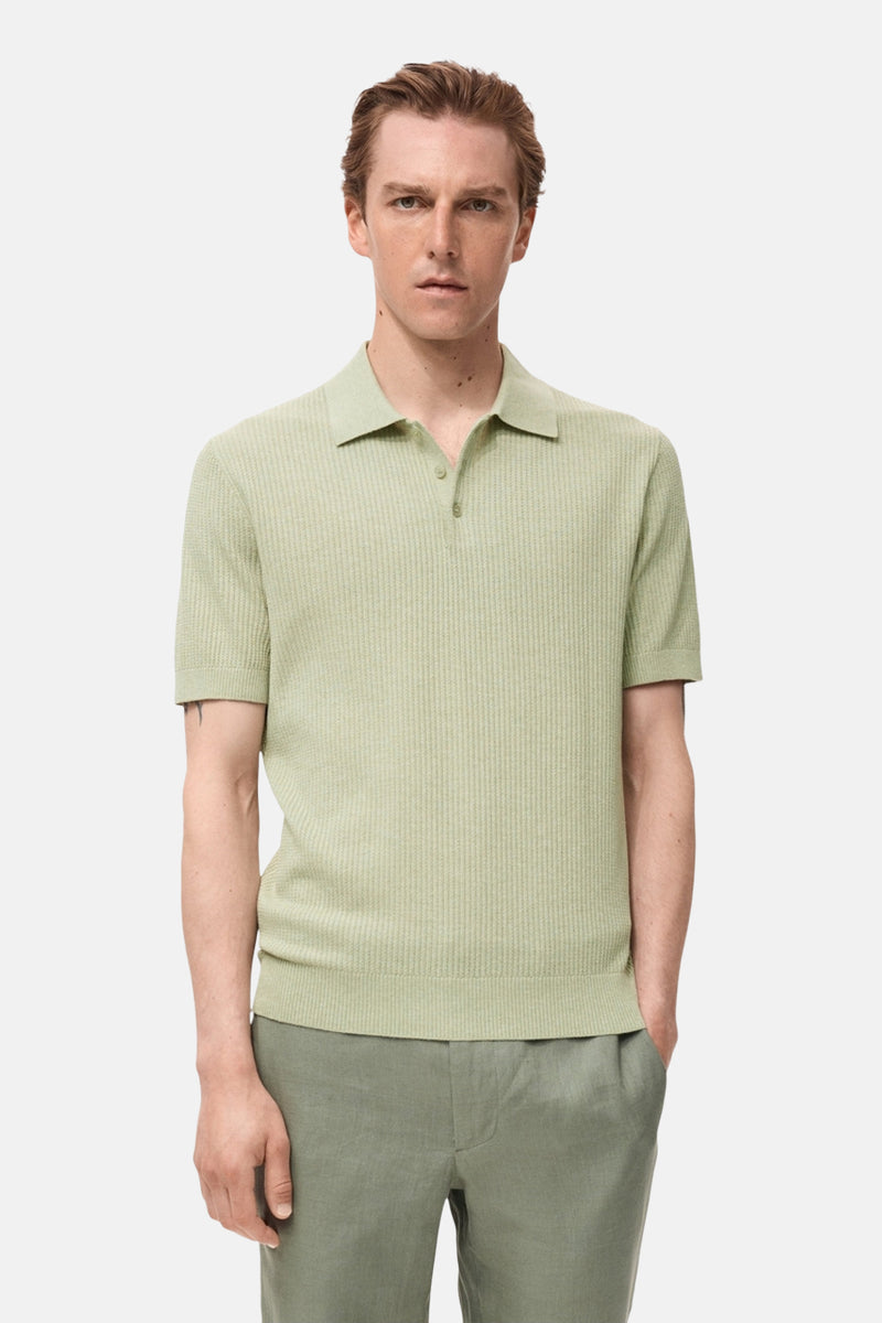 Groen poloshirt met korte mouwen van MANGO, in ribgebreide stof, gedragen met een groene broek.