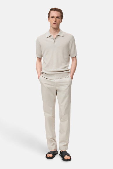Ecru T-shirt met korte mouwen van MANGO, gedragen met een beige broek en zwarte leren sandalen.