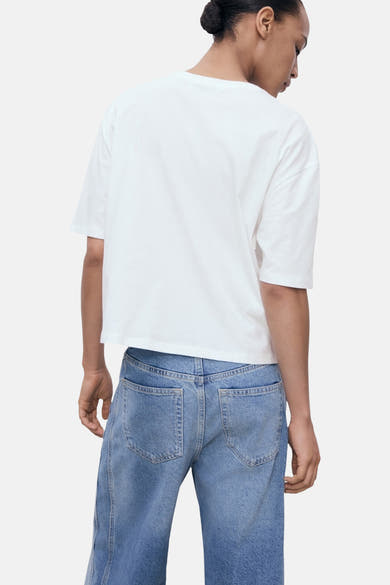 Wit T-shirt met korte mouwen van MANGO, gedragen met een spijkerbroek met hoge taille, achtergezicht.