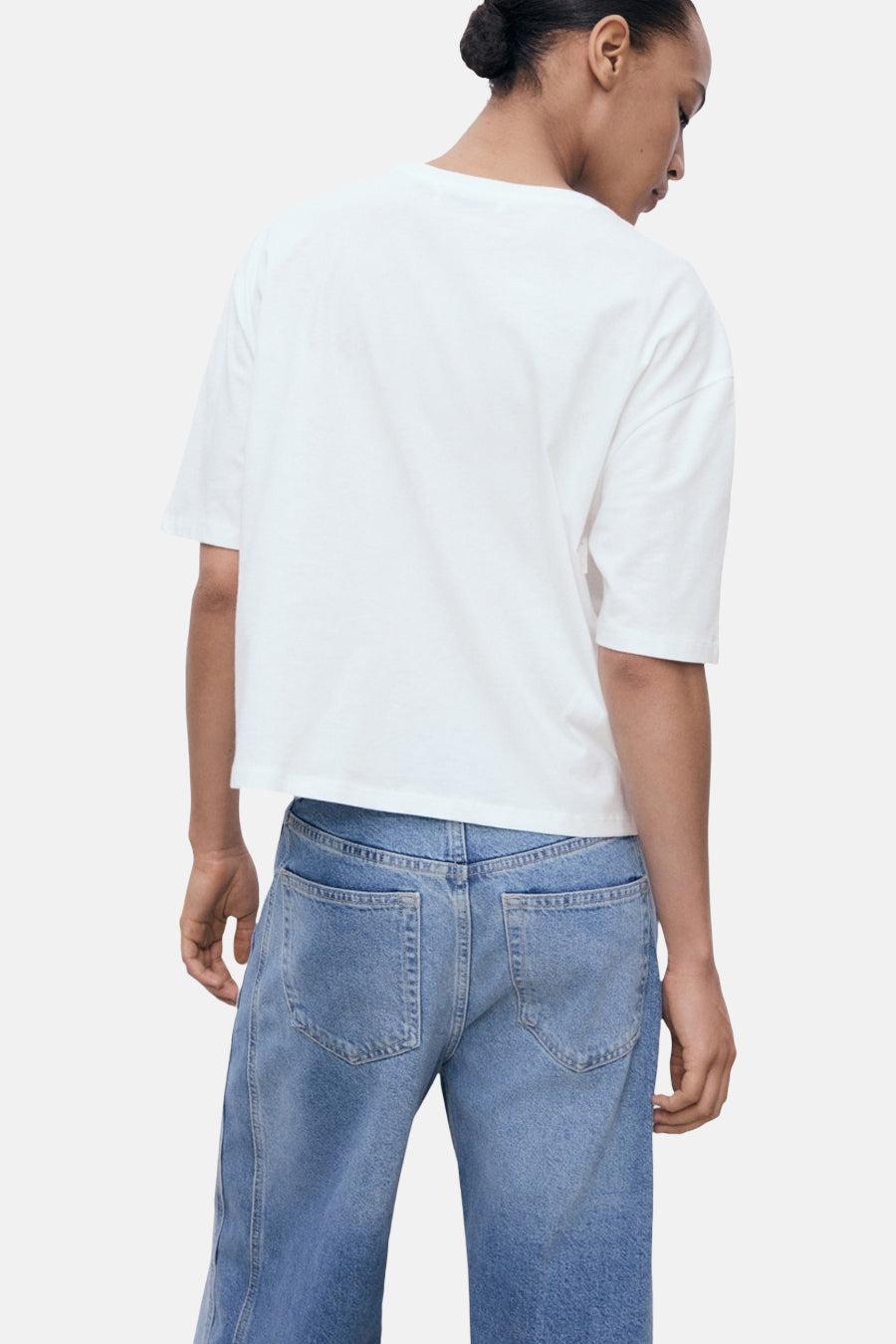 Wit T-shirt met korte mouwen van MANGO, gedragen met een spijkerbroek met hoge taille, achtergezicht.