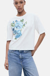 Wit T-shirt met korte mouwen van MANGO, versierd met een blauw bloemenpatroon op de voorkant.