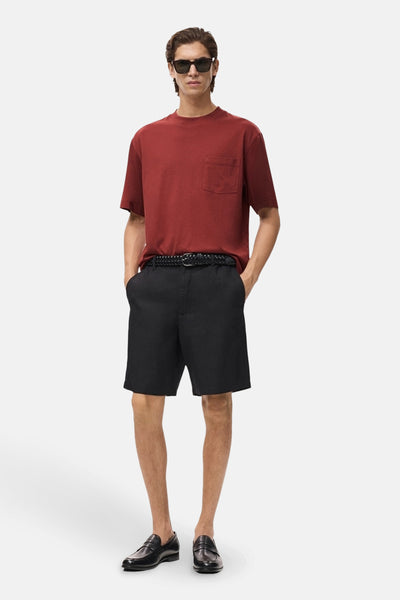 Rood T-shirt met korte mouwen van MANGO, met borstzak, gedragen met een zwarte korte broek en loafers.