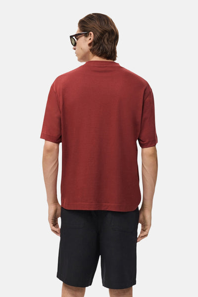 Rood T-shirt met korte mouwen van MANGO, gedragen met een zwarte korte broek en een zonnebril, achteraan gezien.