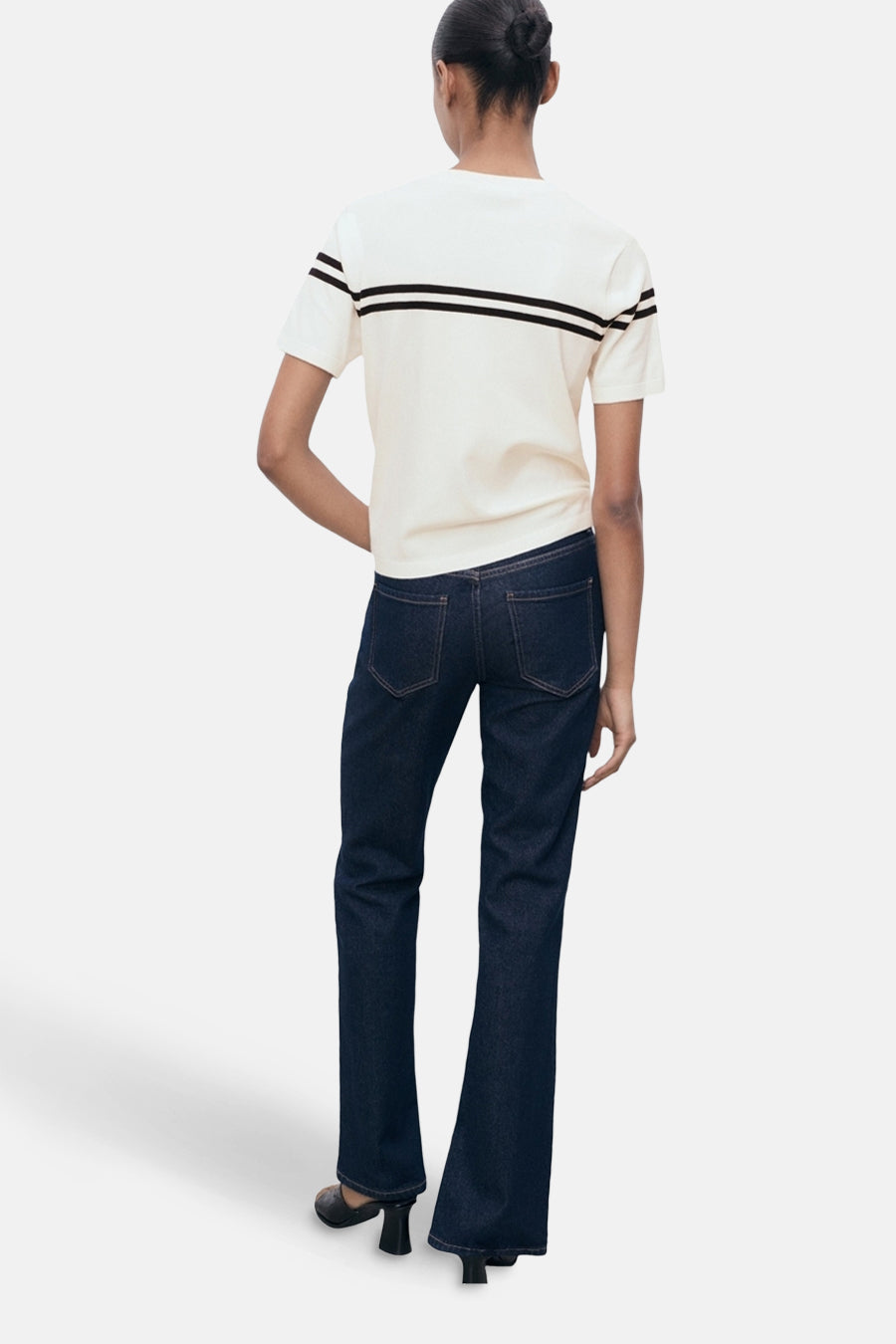 T-shirt à manches courtes blanc de MANGO, rayures noires sur la poitrine, porté avec un jean bleu foncé.