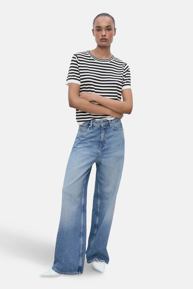 Multikleurig T-shirt met korte mouwen van MANGO, zwart-witte horizontale strepen, gedragen met een lichtblauwe wijde jeans.