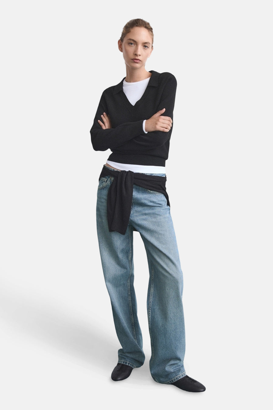 Middelblauwe rechte jeans van MANGO, gedragen met een zwarte trui die aan de taille is geknoopt.