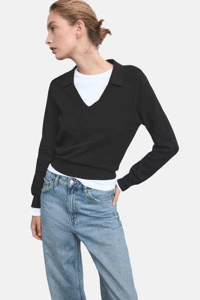 Middelblauwe rechte jeans van MANGO, gedragen met een zwarte trui en een wit T-shirt met V-hals.