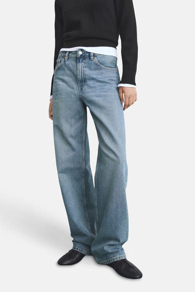 Rechte spijkerbroek in middinblauw denim van MANGO, gedragen met een zwarte trui en zwarte leren schoenen.