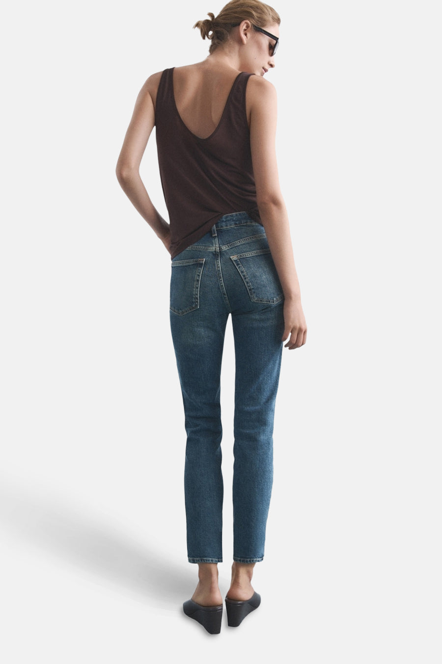 Slim jeans in medium blue denim van MANGO, gedragen met een bruine tanktop en zwarte muiltjes.