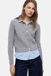 Cardigan gris en maille côtelée de MANGO, porté sur une chemise rayée bleu et un pantalon en denim foncé.
