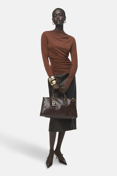 T-shirt à manches longues brun de MANGO, porté avec une jupe noire et un sac à main marron.