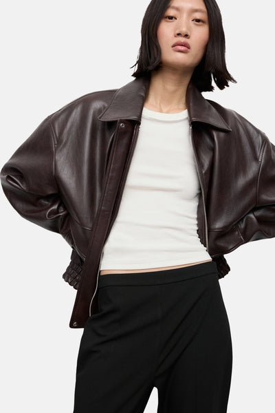 Pantalon noir de MANGO, porté avec un t-shirt blanc et une veste en cuir marron.