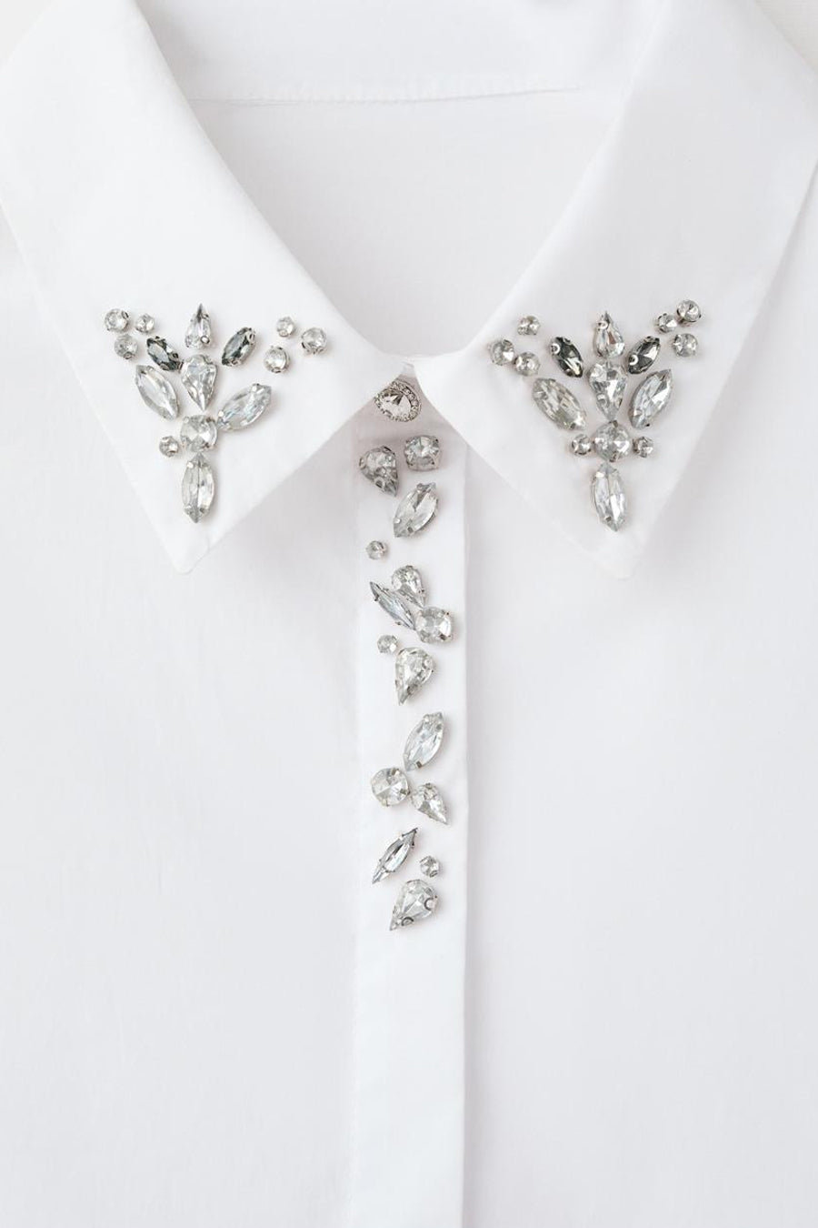 Chemise blanche à manches longues de MANGO, ornée de strass décoratifs sur le col et la patte de boutonnage.
