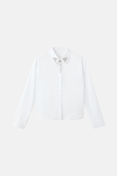 Chemise blanche à manches longues de MANGO, ornée de bijoux au col et sur la patte de boutonnage.