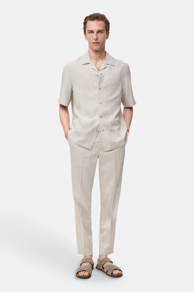 Ecru broek van MANGO, gedragen met een bijpassend overhemd en leren sandalen.