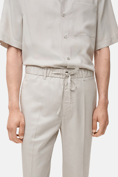 Pantalon écru de MANGO avec cordon de serrage à la taille et coupe droite.