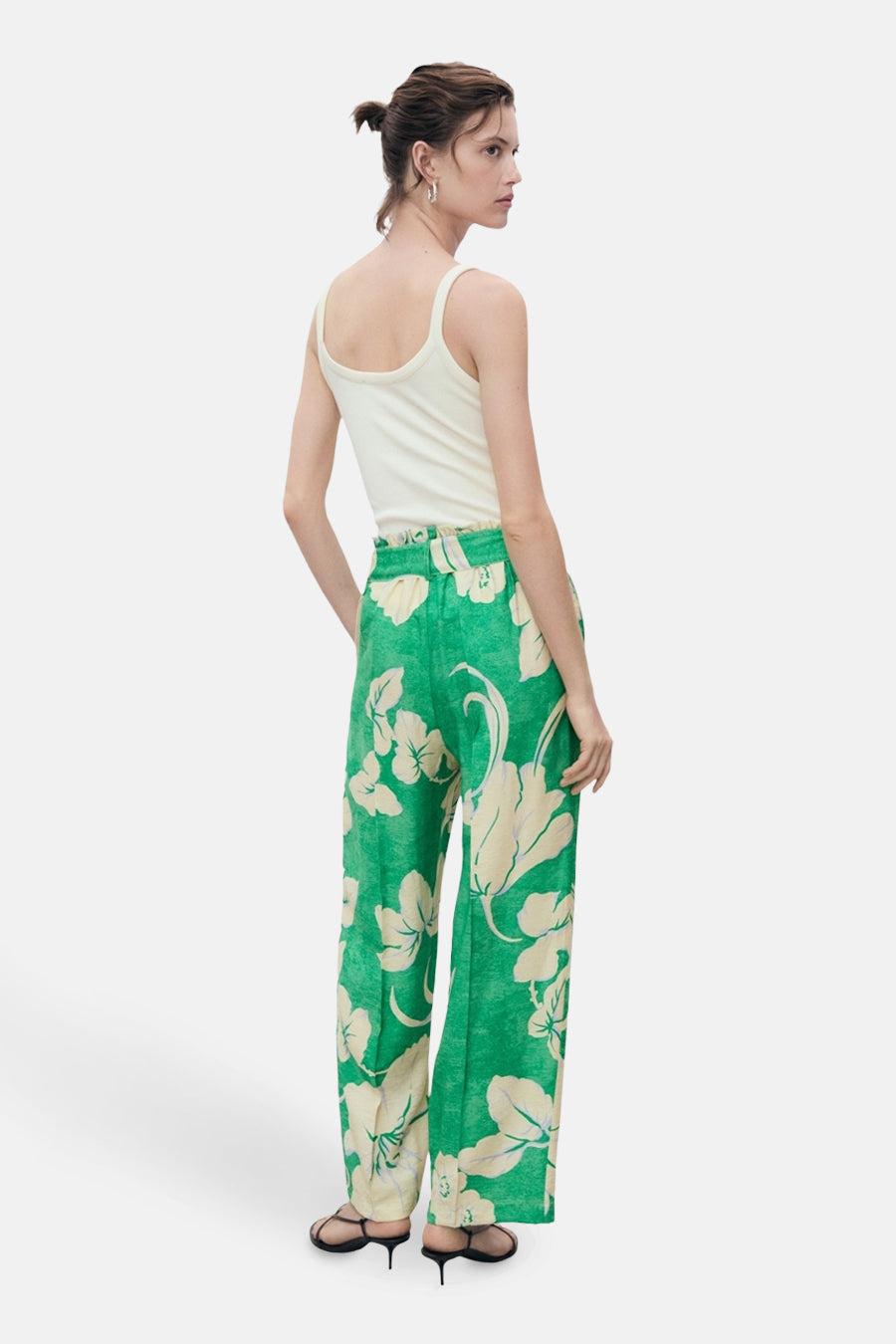 Groene broek met tropische bloemenprint van MANGO, gedragen met een effen witte tanktop en zwarte naaldhakken.