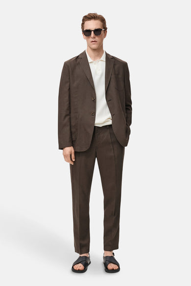Bruine blazer van MANGO, gedragen met een witte polo en zwarte leren sandalen.