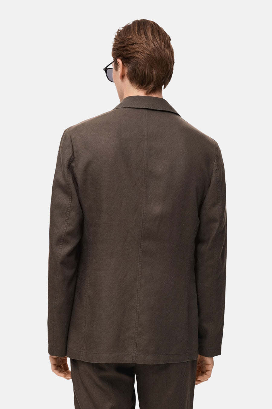 Blazer marron de MANGO, avec une coupe structurée et des lunettes de soleil portées en arrière.