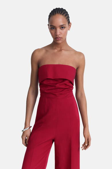 Combinaison rouge by MANGO, coupe droite avec bustier et pantalon large, portée avec un bracelet argenté.
