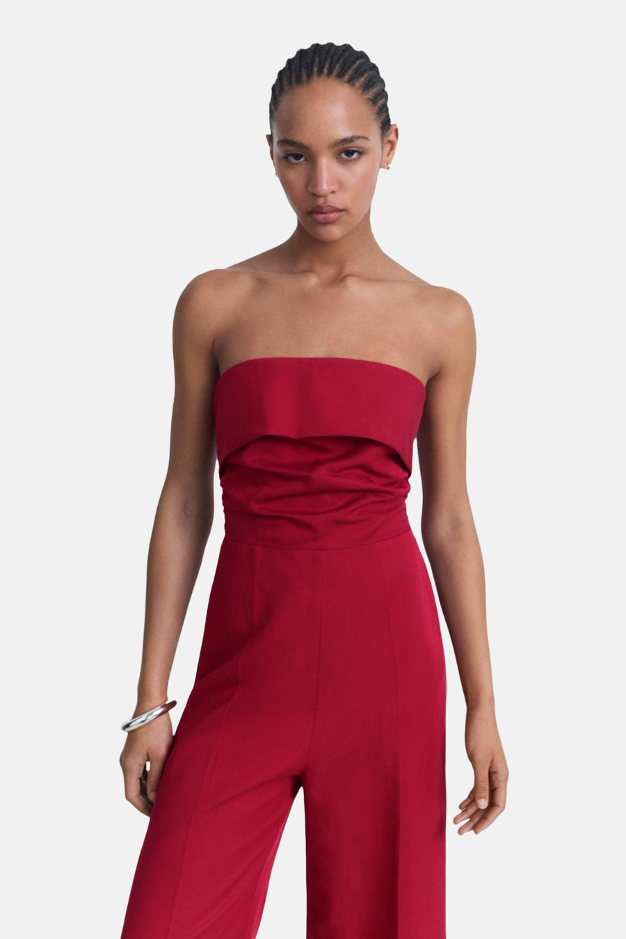 Combinaison rouge by MANGO, coupe droite avec bustier et pantalon large, portée avec un bracelet argenté.
