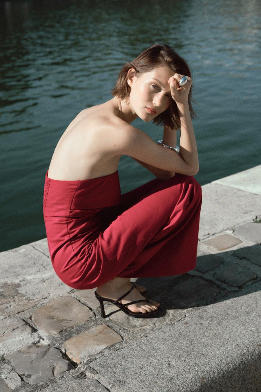 Combinaison rouge de MANGO, sans bretelles, portée avec des sandales à lanières noires et une bague argentée.