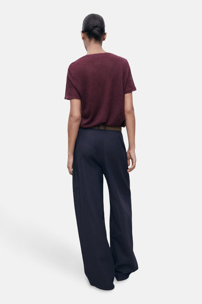 Bordeaux T-shirt met korte mouwen van MANGO, gedragen met een gestreepte broek en een bruine riem, achtergezicht.