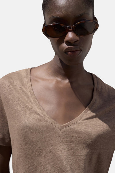 T-shirt à manches courtes brun de MANGO, avec un col en V, porté avec des lunettes de soleil.