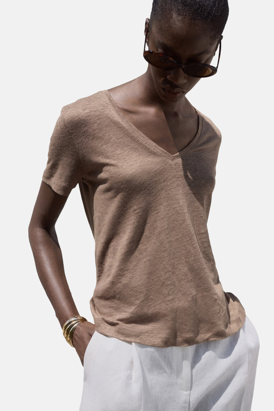 Bruin T-shirt met korte mouwen, van MANGO, gedragen met een witte broek en gouden armbanden.