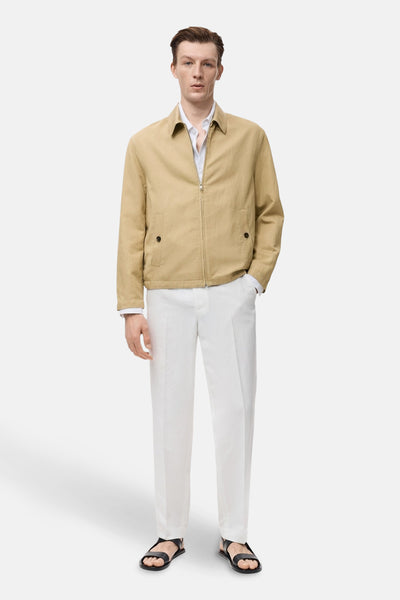 Korte beige jas van MANGO, gedragen met een wit overhemd en een losse witte broek, aangevuld met zwarte sandalen.