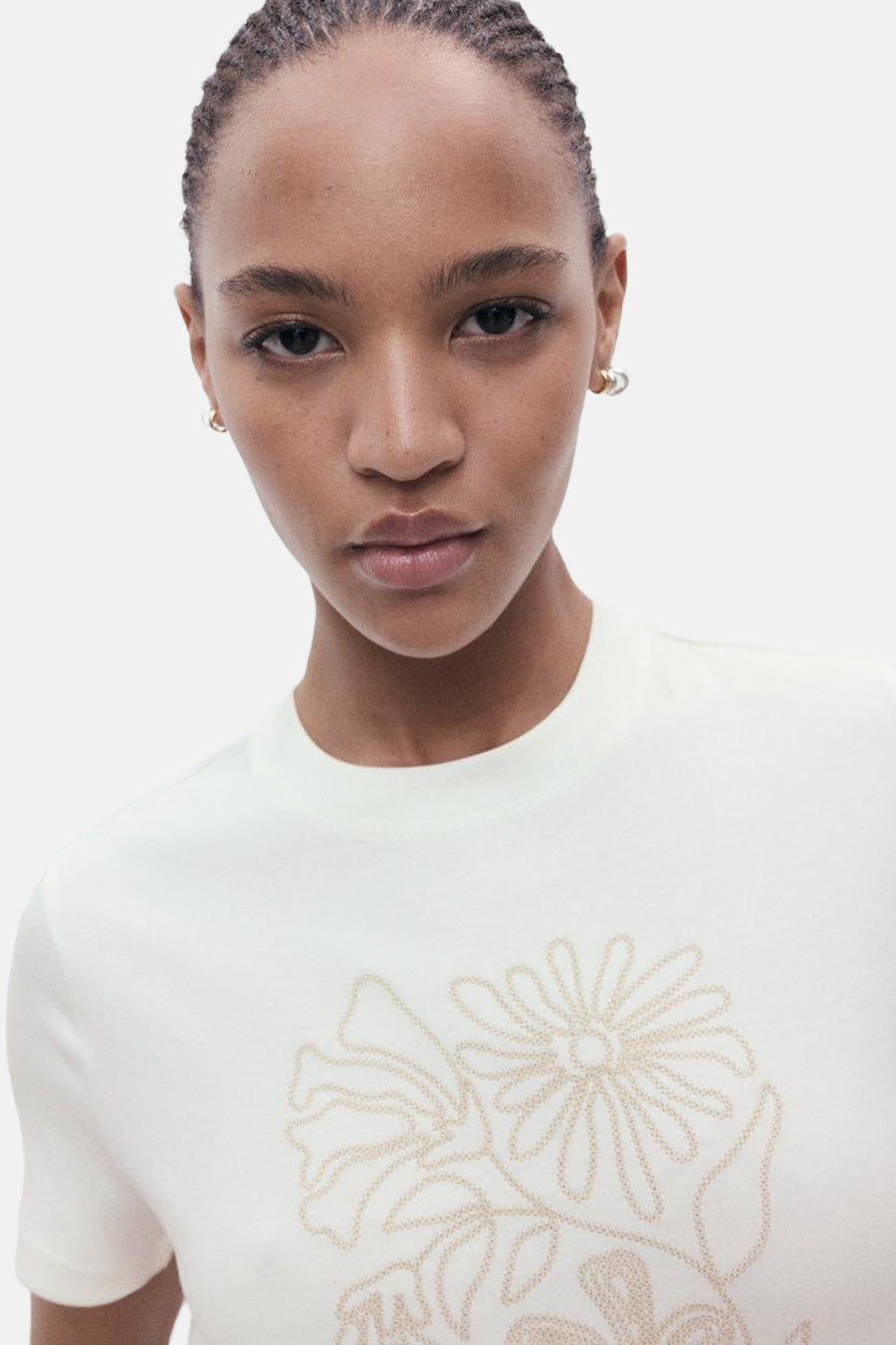 Ecru T-shirt met korte mouwen van MANGO, versierd met een toon-op-toon geborduurd bloemenmotief.