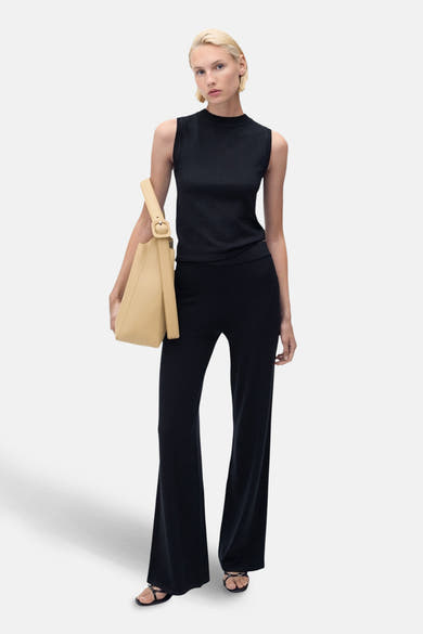 Blauw mouwloos topje van MANGO, gedragen met een zwarte broek met hoge taille en een beige handtas.