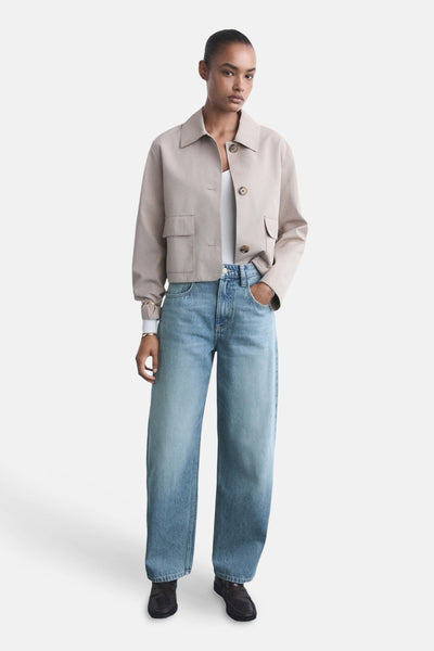 Lichtblauwe jeans van MANGO, gedragen met een beige jas en zwarte schoenen.