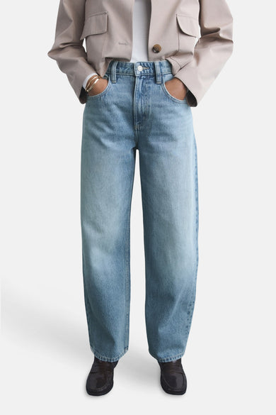 Lichte blauwe jeans van MANGO, gedragen met een beige jas en zwarte mocassins.