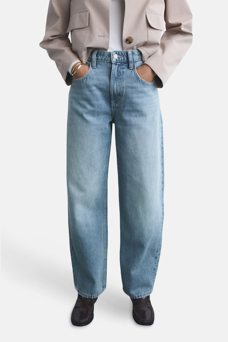 Lichte blauwe jeans van MANGO, gedragen met een beige jas en zwarte mocassins.