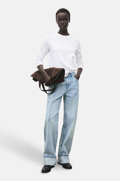 Lichtblauwe rechte jeans van MANGO, gedragen met een wit T-shirt met lange mouwen en een bruine suède handtas.