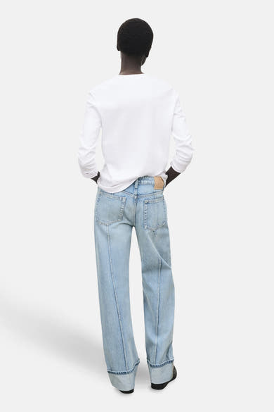 Lichtblauwe rechte jeans van MANGO, met brede omslagen en een wit T-shirt met lange mouwen.