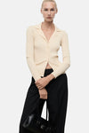 Gele ribgebreide cardigan van MANGO, gedragen met een zwarte broek en een zwarte handtas.