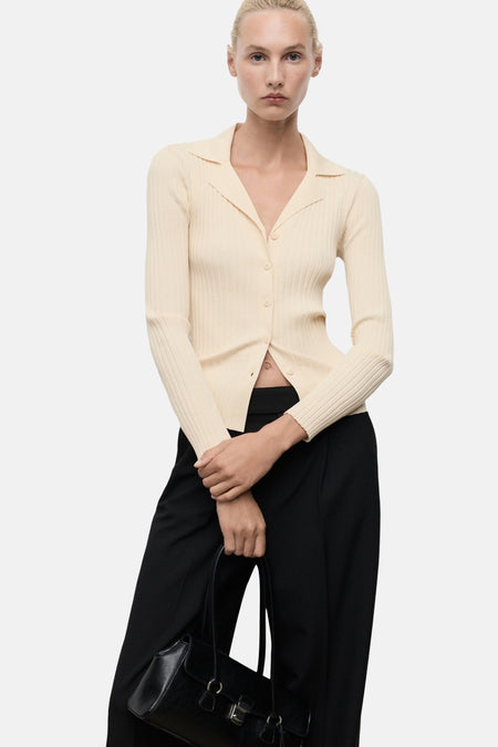 Gele ribgebreide cardigan van MANGO, gedragen met een zwarte broek en een zwarte handtas.